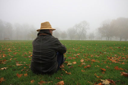 Mensch im Nebel auf einer Wiese sitzend